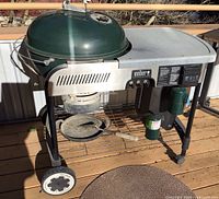 Full view of Weber grill on stand with propane cylinder and spatula on shelf