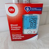 Front view of boxed Life Brand Blood Pressure Monitor with packaging showing product image and key features.