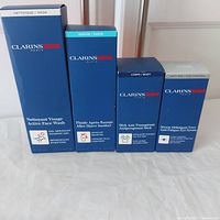 Lot of four Clarins Men products in original blue boxes displayed upright.
