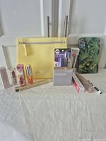Photo showing entire make up lot with yellow Philosophy makeup bag and boxed makeup products arranged in front and around bag.