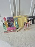 Photo showing all makeup items arranged in front of white cabinet doors including boxed and unboxed items plus yellow Philosophy makeup bag.