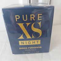 Front view of the sealed navy blue box with gold text Pure XS Night and brand name Paco Rabanne.