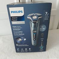 Front of Philips 7000 Series electric shaver box showing model S7882 with SkinIQ technology and key features like travel pouch, pop-up trimmer, and wet & dry use.