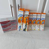 Overall lot showing 2 Spinbrush powered toothbrushes, multiple replacement brush head packs, and 6 tubes Colgate Sensitive toothpaste.