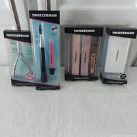 Overview photo showing all four new Tweezerman grooming tools in original packaging on table surface