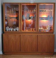 Front view of entire two‐section teak wall unit/hutch showing upper glass display and lower cabinet.