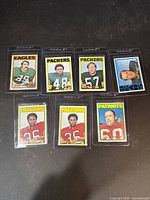 Seven vintage 1970s football trading cards placed horizontally showing player names, numbers and teams including Eagles, Packers, Falcons, Patriots.