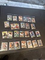 Spread of over 20 1984 Topps NFL football trading cards laid out on black surface showing front designs and player images