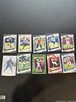 Image showing all 10 Panini Absolute football trading cards from 2022, each featuring various NFL players from different teams, arranged on a surface.