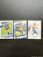 Three Cooper Kupp football trading cards in Los Angeles Rams uniform from 2023 Panini series laid out on plain black background.