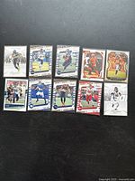Ten different NFL trading cards laid out on black surface showing players from multiple teams with bright, detailed action photography and team logos.