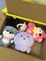 Top view of four plush toys in box with tape measure for scale
