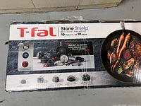 Front of sealed box showing brand, model and image of cookware pieces