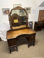Full view of antique walnut finish kneehole vanity with tilting mirror, ornate French Provincial style with turned posts and carved drawer fronts.
