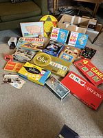 Overview photo showing assortment of vintage board games including Clue, Careers, Yahtzee, Scribbage, Probe, Hexed, Booby-Trap, Chinese Checkers (missing marbles), plus puzzles, blocks, art materials.