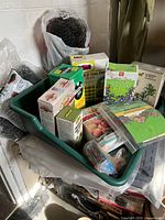 Soil mixing tray containing various gardening products including fertilizer packets, plant food, and garden netting