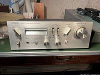 Front view of silver-faced panel showing power switch, speakers selector, VU meters, function knob and balance/volume controls