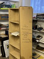 Boxed IKEA Flärke bookshelf standing upright with visible product information written on box.