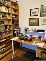 Bookshelf against wall with some books and papers around, showing the top half and base.