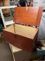 Open wooden box showing interior, hinged lid, and metal latch.