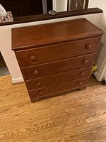 Front view of wooden chest of drawers showing four drawers and wooden knobs, cedar stain finish.