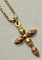 Close-up image of the cross pendant showing the textured grape cluster and leaf details in yellow and rose gold.