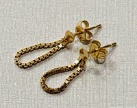 Side angled view highlighting the loop shape and box-link chain detail of the yellow gold earrings.