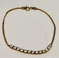 Full view of the 10K yellow gold bracelet featuring a row of clear zircon stones.