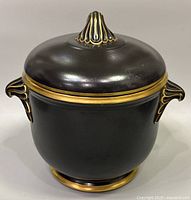Overall front view of the black Coalport lidded jar with gold trim and finial.