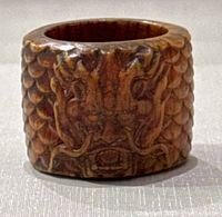 Front view showing the dragon face carving and scaled texture on wooden ring.
