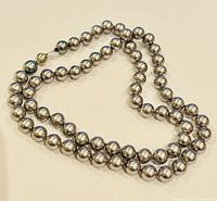 Close-up image of the necklace arranged in a loop showing the smooth, shiny surface and color of the beads.