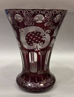 Close-up front view of the vintage ruby red cut crystal vase showing clear floral and swirl cut patterns over ruby red glass