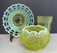 Three vaseline glass pieces grouped: bowl, plate on stand, footed vase.