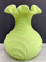 Front view of vintage pale lime green satin Uranium glass vase showing ruffled edge and swirl pattern