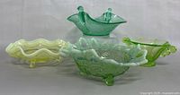 Four glass bowls and dishes: yellow uranium ruffled bowl, green frog footed bowl, green bird dish with two bird figures, green opalescent crimped edge dish.