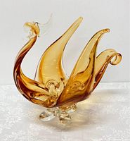 Wide view of the full glass bird figurine showing the sweeping wing shapes and clear glass feet with amber tint.
