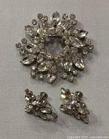 Front view of the Sherman rhinestone brooch with clear multi-shaped rhinestones and floral design along with matching earrings.