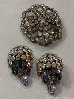 Brooch and earrings visible, showing clear rhinestone brooch with bow design and multicolored rhinestone earrings.