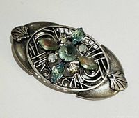 Angled front view showing overall design, filigree work and multicolored glass stones.