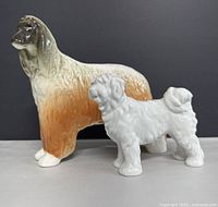 Front view of two dog figurines showing Afghan Hound with brown/cream hues and white Pekingese