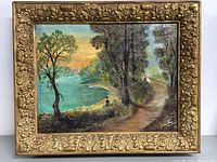Full frontal view of the framed painting showing landscape with lake, trees, path, and sunset with visible ornate gold frame.