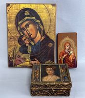 Photo showing two vintage religious wooden wall icons and one wooden trinket box with hand painted female portrait on top and decorative colored motifs on sides.