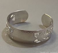 Image showing the side view of the sterling silver cuff bracelet, highlighting the cut-out floral design on the band.