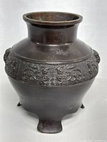Front view of small tripod metal vase showing embossed pattern and wide mouth