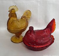 Amber pedestal hen dish (left) and red nest-style hen dish (right) side by side