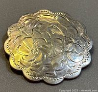 Front view showing scalloped edge and engraved floral scroll motif