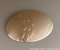 Top view of the oval silver brooch showing engraved leaf design with minor surface scratches and patina.