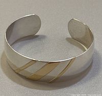 Front view of cuff bracelet showing three diagonal gold stripes on polished silver