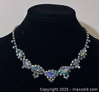 Front view of the vintage Continental rhinestone necklace on a black display stand, showing marquise and round blue iridescent rhinestones set in silver-tone metal.