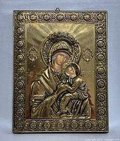 Front view of vintage gold-tone Greek religious wall icon showing Virgin Mary and baby Jesus with ornate embossed border.